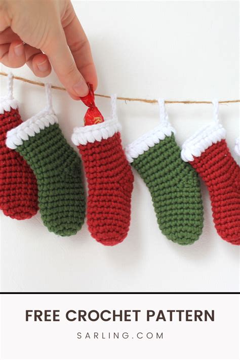 a hand is holding a red and green knitted stocking hanging from a line