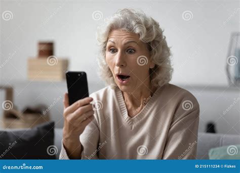 Shocked Elderly Lady Staring At Smartphone With Open Mouth Stock Photo