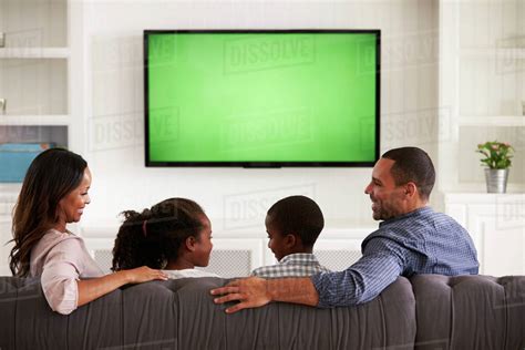 Parents And Children Watching Tv Looking At Each Other Stock Photo