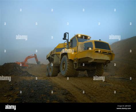 Earth Moving Truck With Lights On And Digger In Misty Quarry Stock