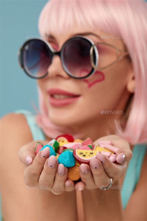 close up of a flirtatious female model on blue background wearing a pink wig holding different