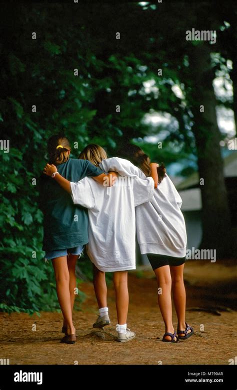 Three Girls Walk With Their Arms Across Each Others Shoulders At