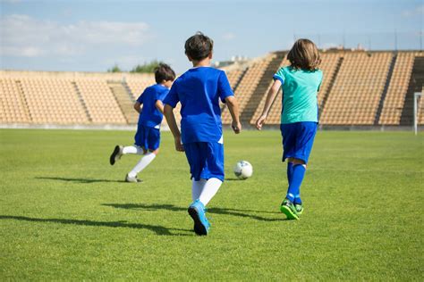 Three Boys Playing Soccer On A Soccer Field · Free Stock Photo