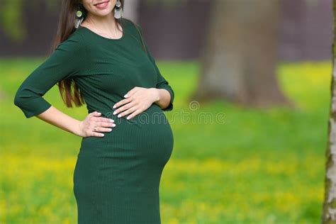 pregnant belly closeup closeup on the belly of a pregnant woman wearing a long green dress a