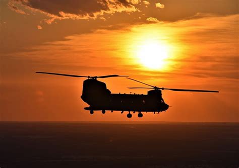 The Sunset Is Visible Behind A Ch 47 Chinook Helicopter Operated By