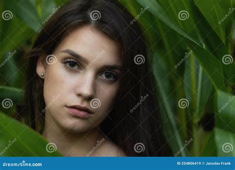 Long Haired Brunette Young Woman Poses Among The Green Plants Stock