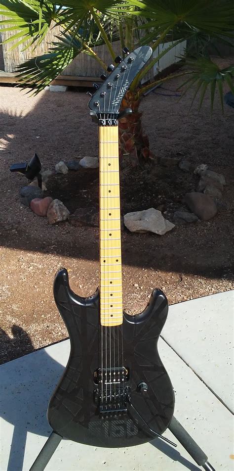 An Electric Guitar Sitting On Top Of A Cement Slab Next To A Palm Leaf Tree