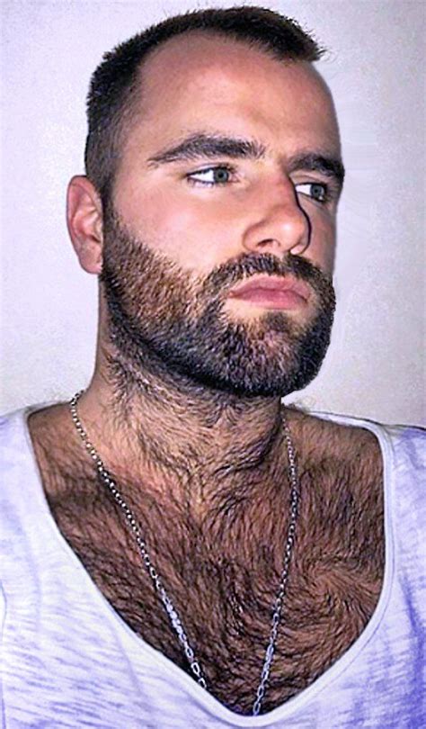 A Man With A Beard And No Shirt Is Looking At The Camera While Wearing
