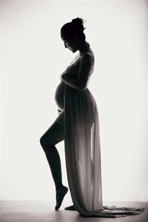 A Pregnant Woman Is Posing For A Black And White Photo With Her Leg Up In The Air