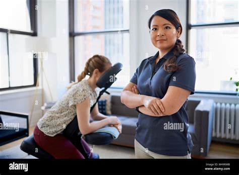 Portrait Of A Chinese Woman Massage Therapist Giving A Neck And Back Pressure Treatment To An