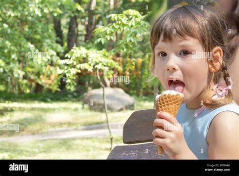 Cute Little Girl Eating Ice Cream In The City Park On A Summer Sunny