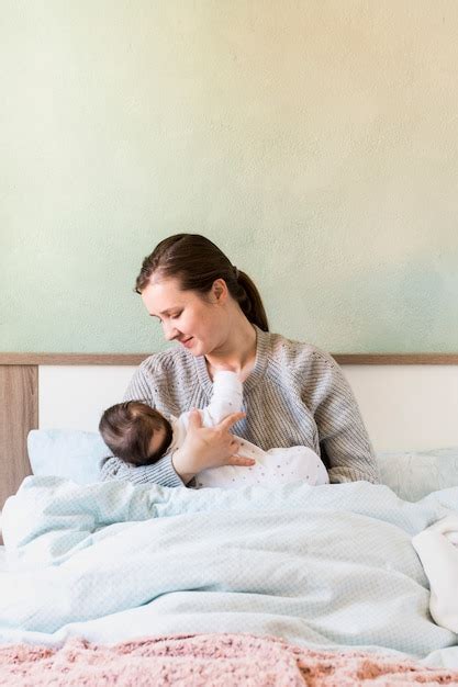 Madre Con Bebé En Brazos En La Cama Foto Gratis