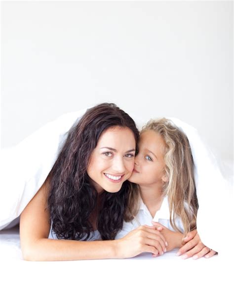 premium photo delighted mother and her daughter looking at the camera on the bed
