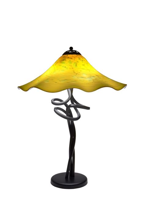 A Table Lamp With A Yellow Glass Shade On It S Base And A Black Metal Stand