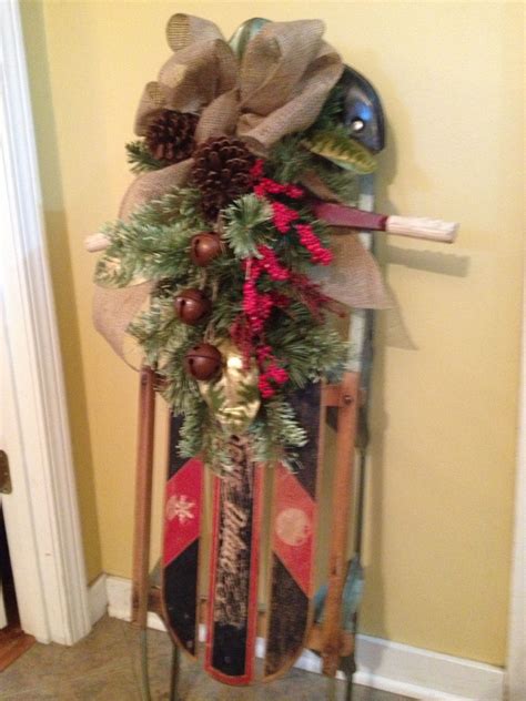 An Old Sled Decorated With Christmas Decorations And Pine Cones Is Hung