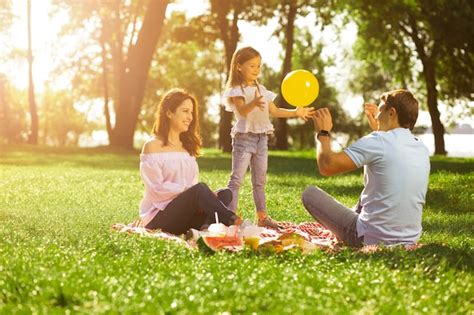Niña Jugando Al Globo Con Sus Padres En El Parque En Un Día Soleado