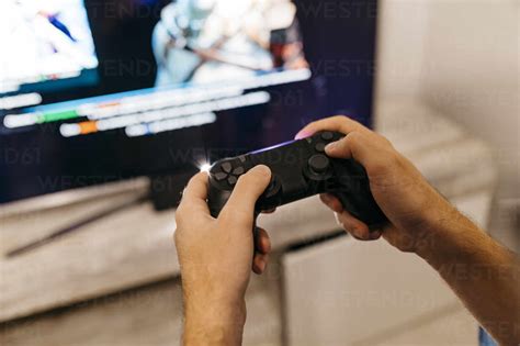 Hands Of Male Gamer Holding Controller While Playing At Home Stock Photo