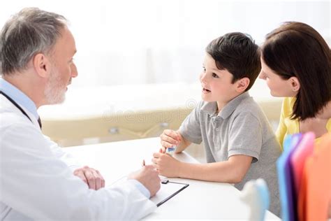 Mature Pediatrician Making Recommendations For Small Patient Stock