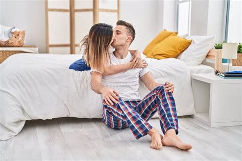 Man And Woman Couple Sitting On Bed Hugging Each Other And Kissing At