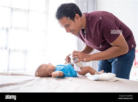 Portrait Of Asian Father Changing His Infant Baby Diaper At Home Stock