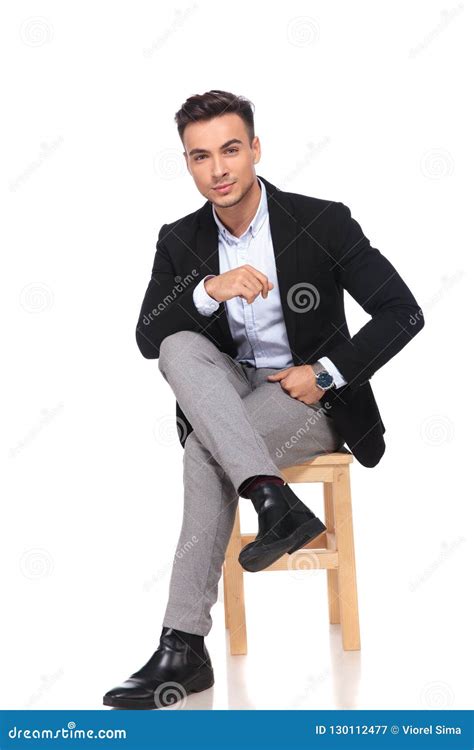 Attractive Businessman Sitting On Wooden Chair With Legs Crossed Stock