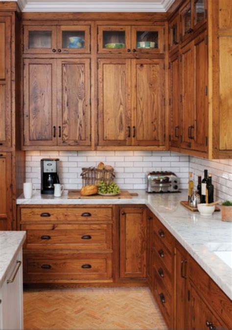 A Kitchen With Wooden Cabinets And White Marble Counter Tops Along