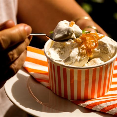 A Person Is Eating Ice Cream In An Orange And White Striped Bowl
