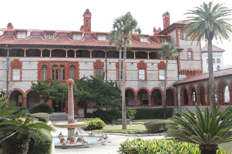 An Old Building With Palm Trees In The Front Yard And Fountain On The