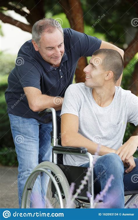 Dad Walking With Disabled Son In Wheelchair At Park Stock Photo Image