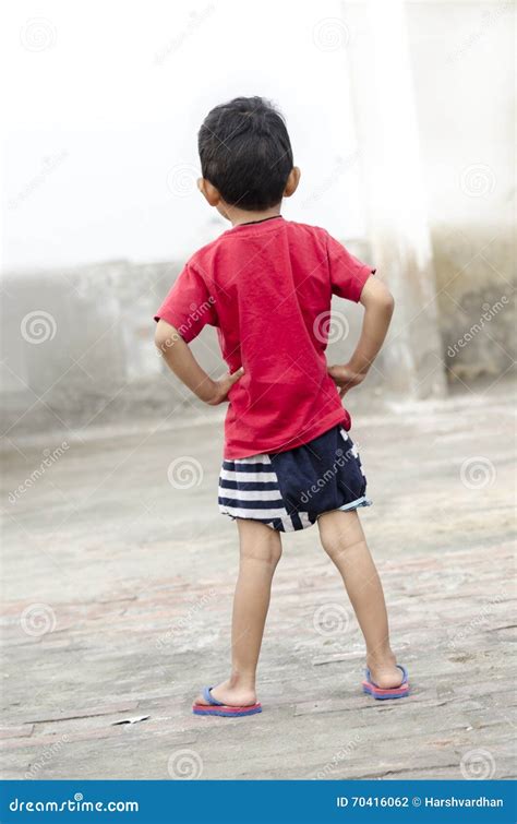 Boy Child Standing And Waiting Hands On Hips Rear View Stock Photo