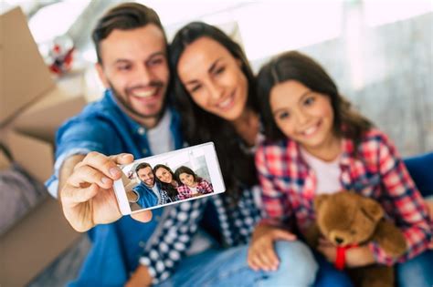 Foto de cerca la familia alegre está tomando selfie juntos en su nueva