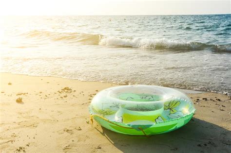 Green Inflatable Round Tube On The Sand Beach With Sunlight In The