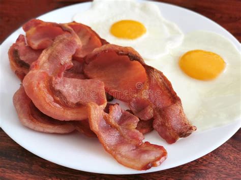 Crispy Bacon With Eggs In A White Plate On Wood Table Stock Photo