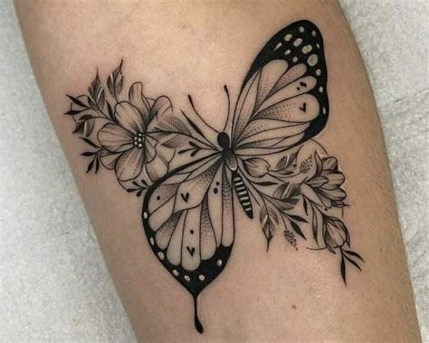 A Black And White Butterfly With Flowers On It S Back Side Arm Tattoo