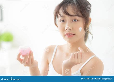 Beautiful Young Asian Woman Happy Applying Cream Or Lotion With Moisturizer To Skin Face Stock