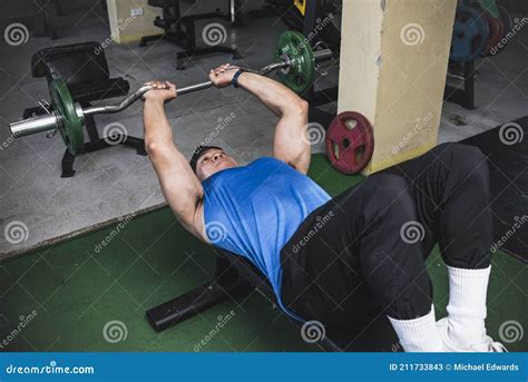 An Athletic Asian Male Does A Set Of Lying Tricep Extensions Also