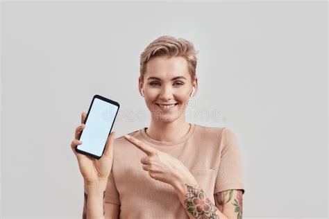 Portrait Of Tattooed Woman With Pierced Nose And Short Hair In Wireless Earbuds Or Earphones