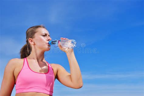 Portrait Of Young Woman Drinking Water After Jogging Stock Photo