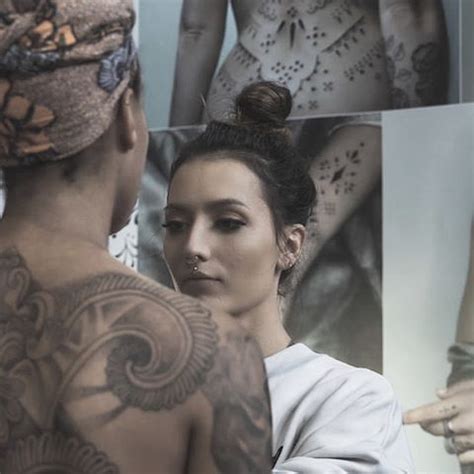 A Man And Woman Standing Next To Each Other With Tattoos On Their Arms Behind Them Are Pictures