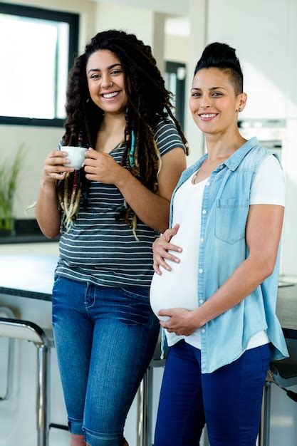 Premium Photo Portrait Of Pregnant Lesbian Couple Standing Together And Smiling In Kitchen