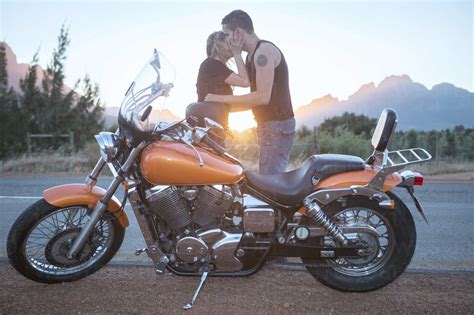 Couple Kissing Next To Motorcycle By The Roadside Stock Photo