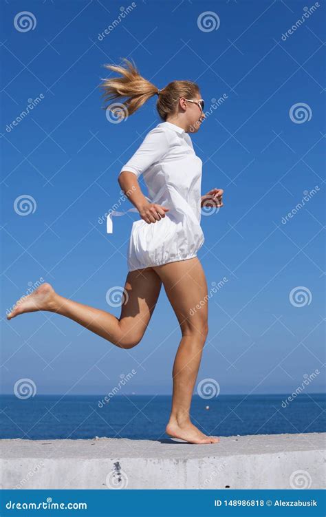 Barefoot Girl In White Short Dress Running Along Breakwater Stock Photo
