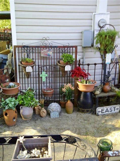 Many Potted Plants Are On Display In Front Of A House With An Iron Fence