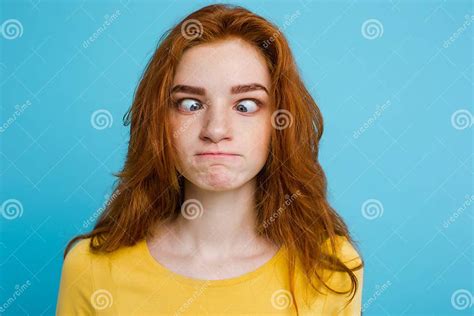 headshot portrait of happy ginger red hair girl with funny face looking at camera pastel blue