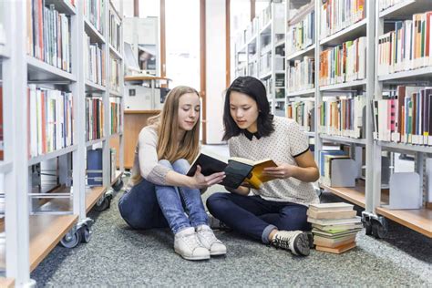 us nanny institute two teenage girls sitting on the floor in a public library reading in a book