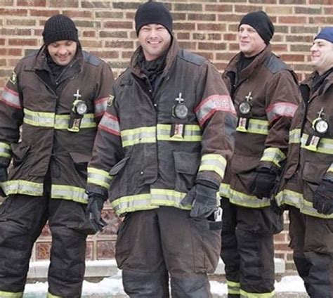 Four Firemen Are Standing In Front Of A Brick Building And One Is