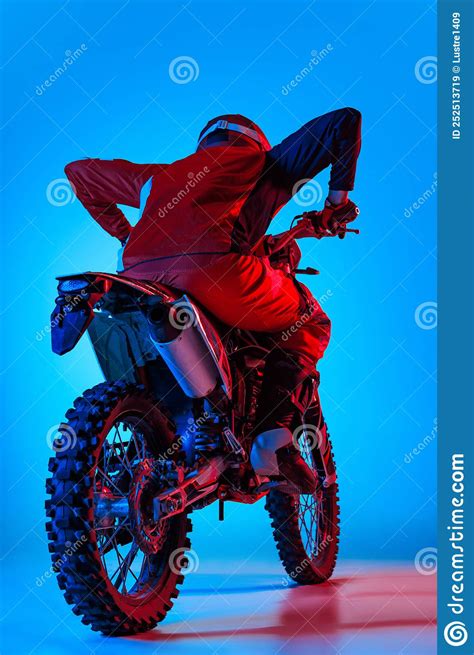 Portrait Of Young Man Biker Posing On Motorbike Isolated Over Blue