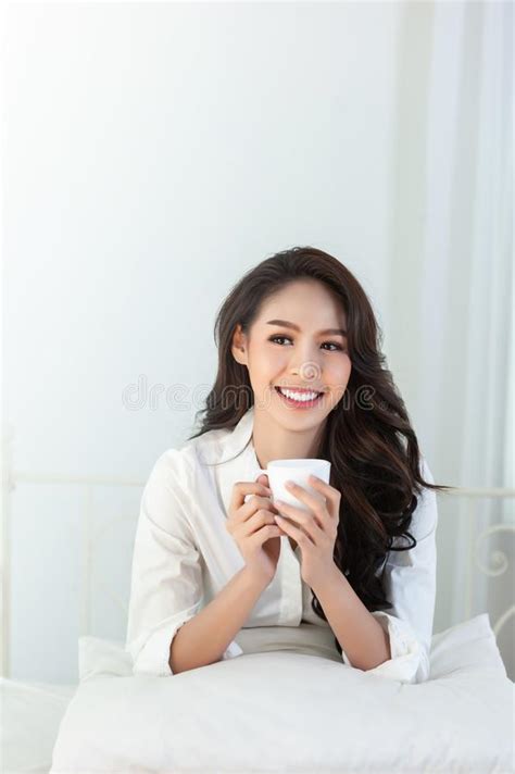 a beautiful asian woman in a white shirt smiling happily on a white bed stock image image of