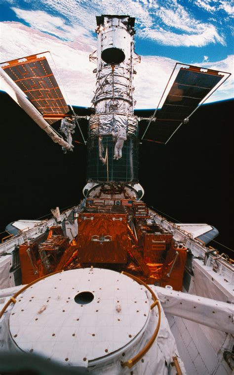 Astronauts Working On A Satellite Docked On The Space Shuttle