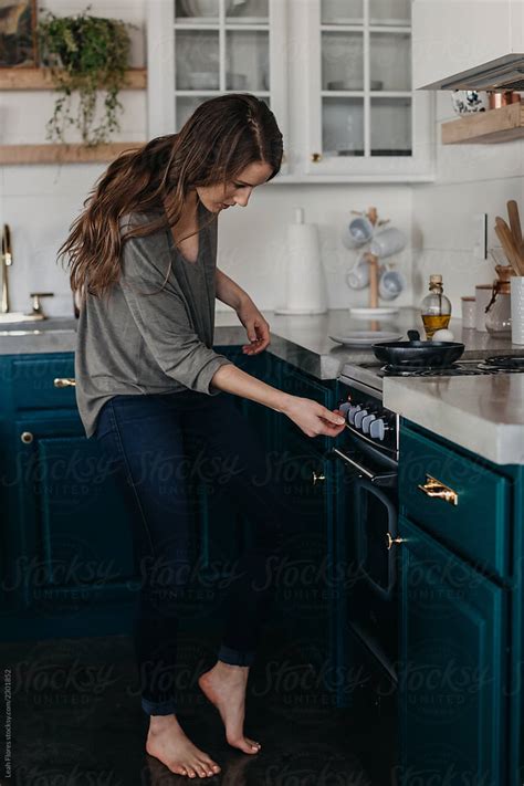 Woman Turning On Stove By Stocksy Contributor Leah Flores Stocksy